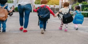 Back to School Safety picture of mom and kids with backpacks crossing the street to get to school