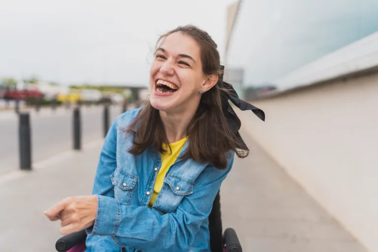 Portrait of young woman with cerebral palsy laughing joyfully outdoors